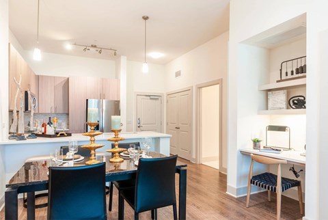A dining room with a table set for two and a kitchen area in the background.