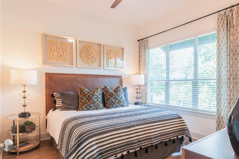 A bedroom with a bed, pillows, and a ceiling fan.