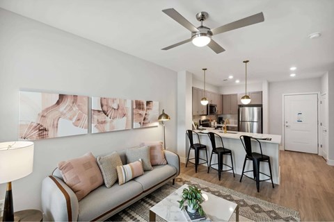 A living room with a grey couch and a ceiling fan.