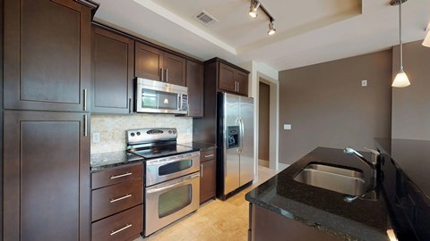 A kitchen with dark brown cabinets and stainless steel appliances.