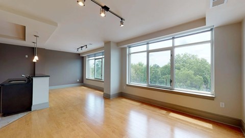 A spacious room with wooden floors and large windows.