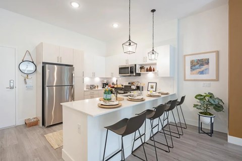 A modern kitchen with a white island and black barstools.
