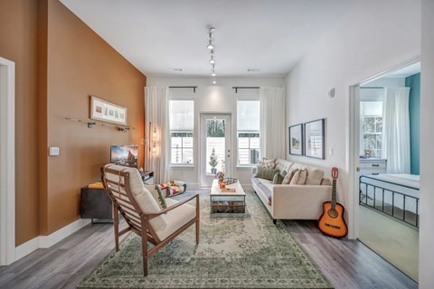A living room with a chair, a couch, a rug, and a guitar.
