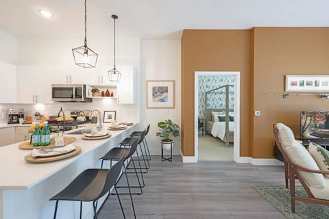 A kitchen with white countertops and black chairs.