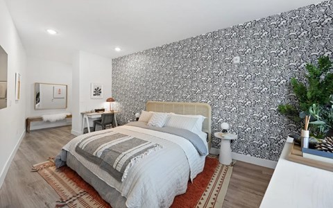 A bedroom with a large bed and a patterned wallpaper.