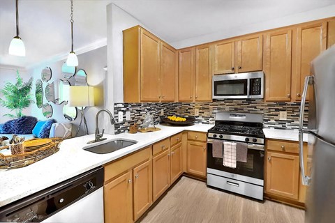A kitchen with wooden cabinets and a stainless steel refrigerator.