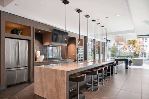 A modern kitchen with a long counter and stools.