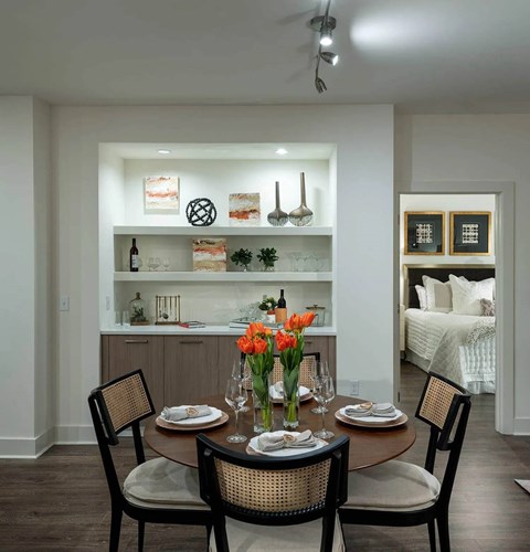 A dining room with a table set for two and a bed in the background.