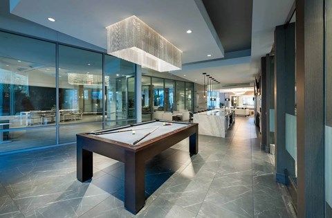 A pool table is in the middle of a room with a glass wall.