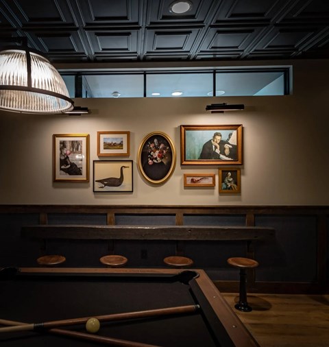 A pool table with a light hanging above it and pictures on the wall.