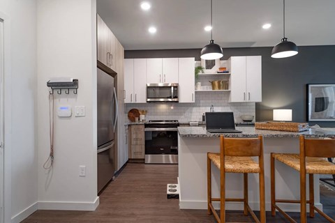 A kitchen with a refrigerator, stove, and bar stools.