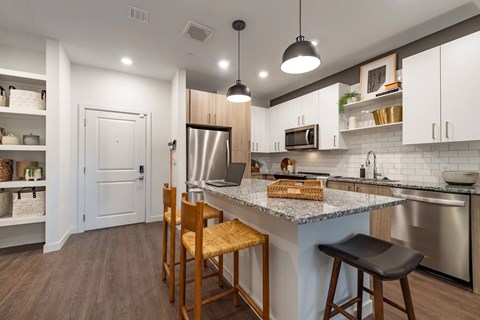 A kitchen with a white counter top and wooden chairs.