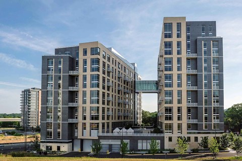 Two modern buildings with large windows and balconies are situated next to each other.