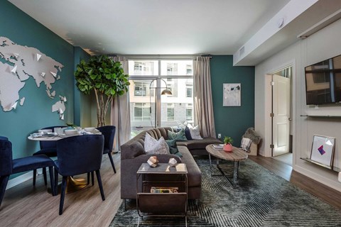 A living room with a world map on the wall and a dining table with chairs.