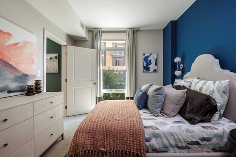 A bedroom with a bed, dresser, and window.