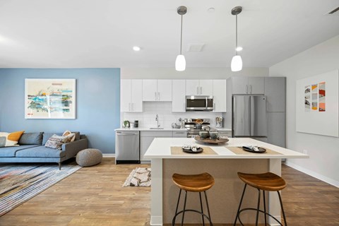 A kitchen with a white countertop and wooden stools.