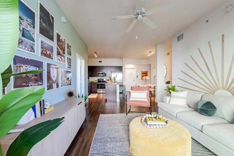A living room with a white couch and a yellow ottoman.