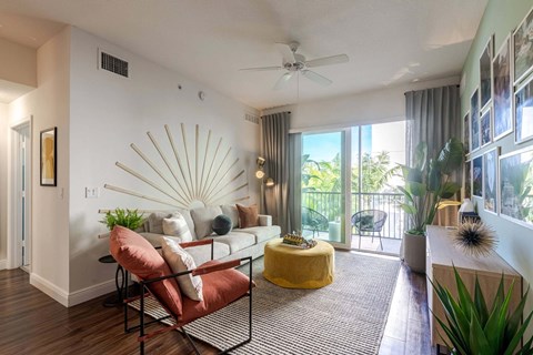 A living room with a yellow ottoman and a red chair.