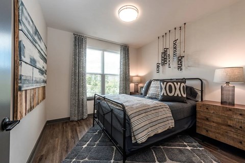 A bedroom with a bed, nightstand, and a window with curtains.