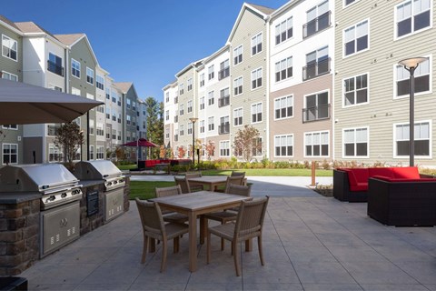 A patio with a table and chairs is surrounded by apartment buildings.