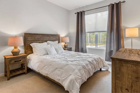 A bedroom with a large bed and two lamps.