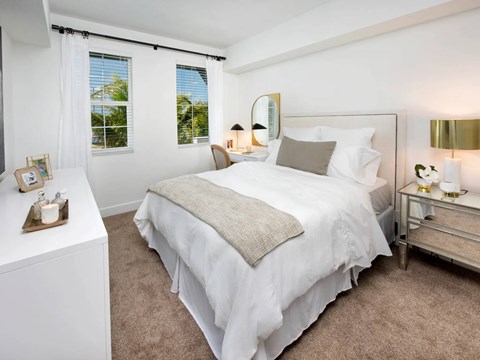 A bedroom with a large bed, a nightstand, and a window with curtains.