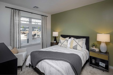 A bedroom with a large bed and a chair by the window.