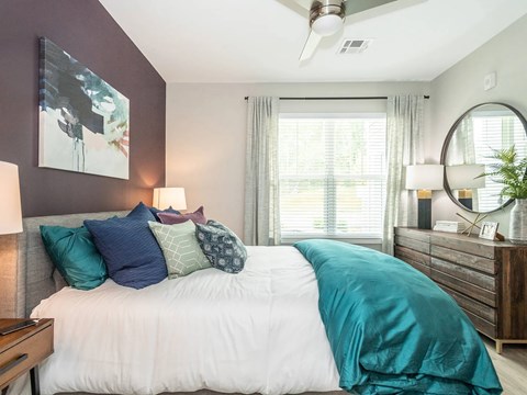 A bedroom with a bed, a ceiling fan, and a mirror.