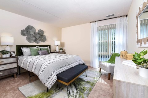 A bedroom with a large bed and a green plant on the side table.