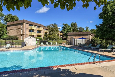 A swimming pool surrounded by lounge chairs and trees.