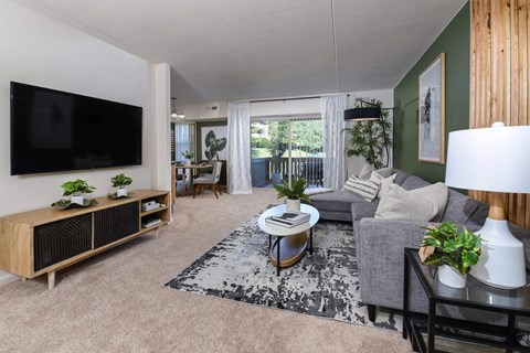 A living room with a grey couch, a black and white rug, and a wooden cabinet.
