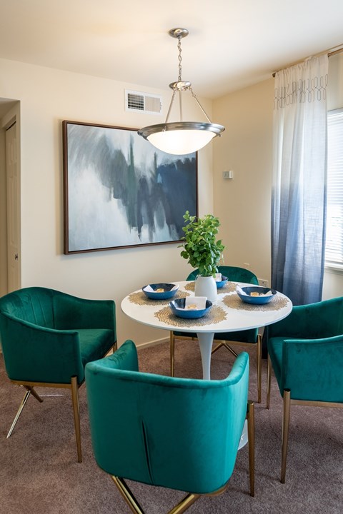 A dining room with a white table and green chairs.
