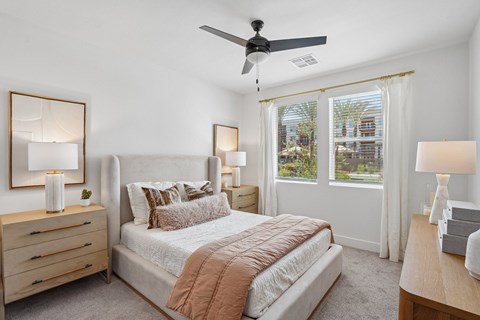A bedroom with a large bed, a ceiling fan, and a dresser with a mirror.