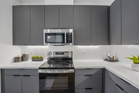 A modern kitchen with a stove top oven and microwave above it.