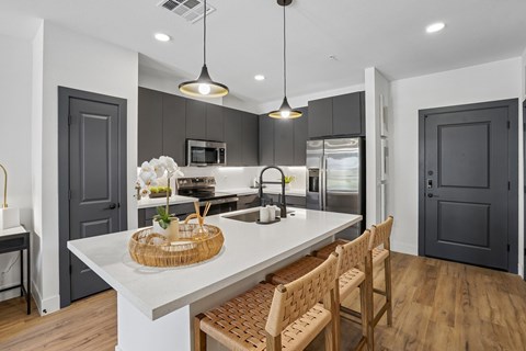 A modern kitchen with a white island and wooden chairs.