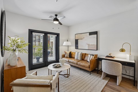 A living room with a brown couch, a white coffee table, and a painting on the wall.