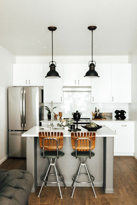 A kitchen with a white counter and two chairs.