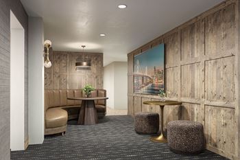 A room with a brown couch, a table with a vase of flowers, and a large painting on the wall.