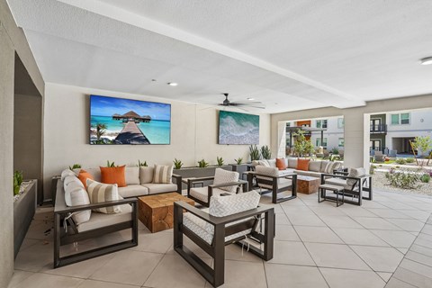 A patio with furniture and a painting of a beach scene.