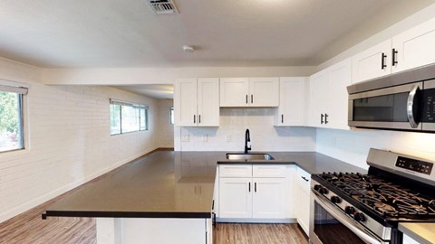 A modern kitchen with white cabinets and a black countertop.