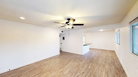 A room with a ceiling fan and wooden flooring.