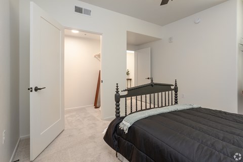 A bedroom with a black bed and a wooden stick leaning against the wall.
