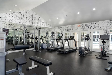 A gym with a variety of equipment including treadmills, weights, and exercise machines.