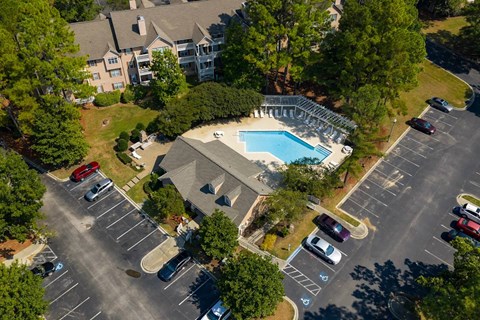 A large swimming pool surrounded by a parking lot and a building in the background.