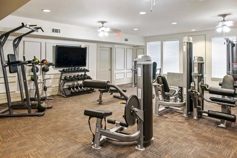 A well-equipped gym with a variety of exercise machines and a flat screen TV mounted on the wall.