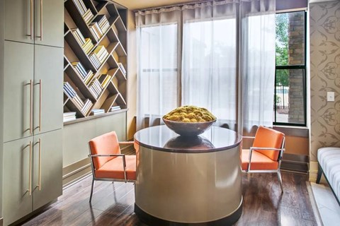 A modern kitchen with a round table and orange chairs.