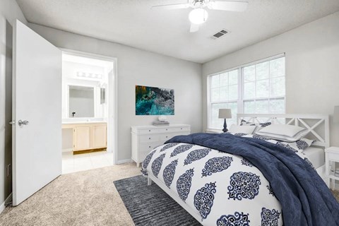 A bedroom with a bed, dresser, and ceiling fan.