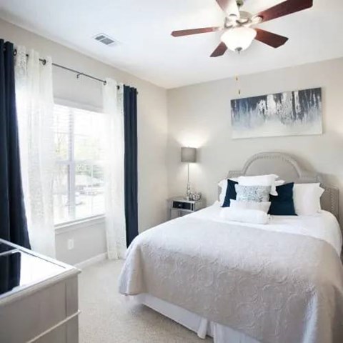 A bedroom with a large bed and a ceiling fan.