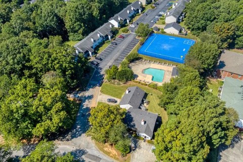 An aerial view of a neighborhood with a blue pool and tennis court.