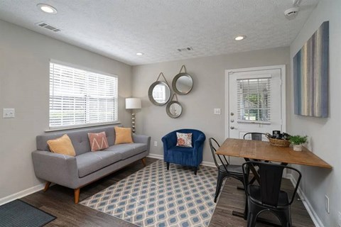 A living room with a grey couch, a blue chair, and a wooden table.